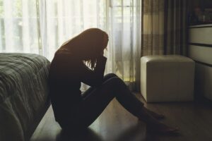 Person sitting on the floor indoors, thinking about the non-fatal overdoses they've experienced